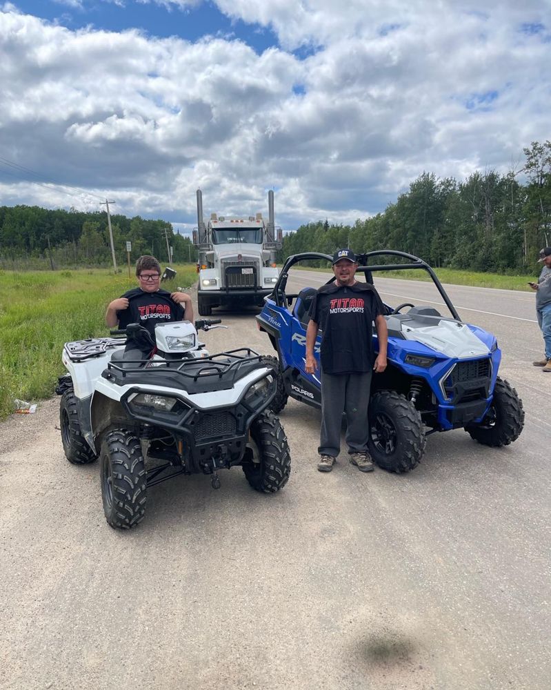 Father and son with their new Polaris ATV and RZR